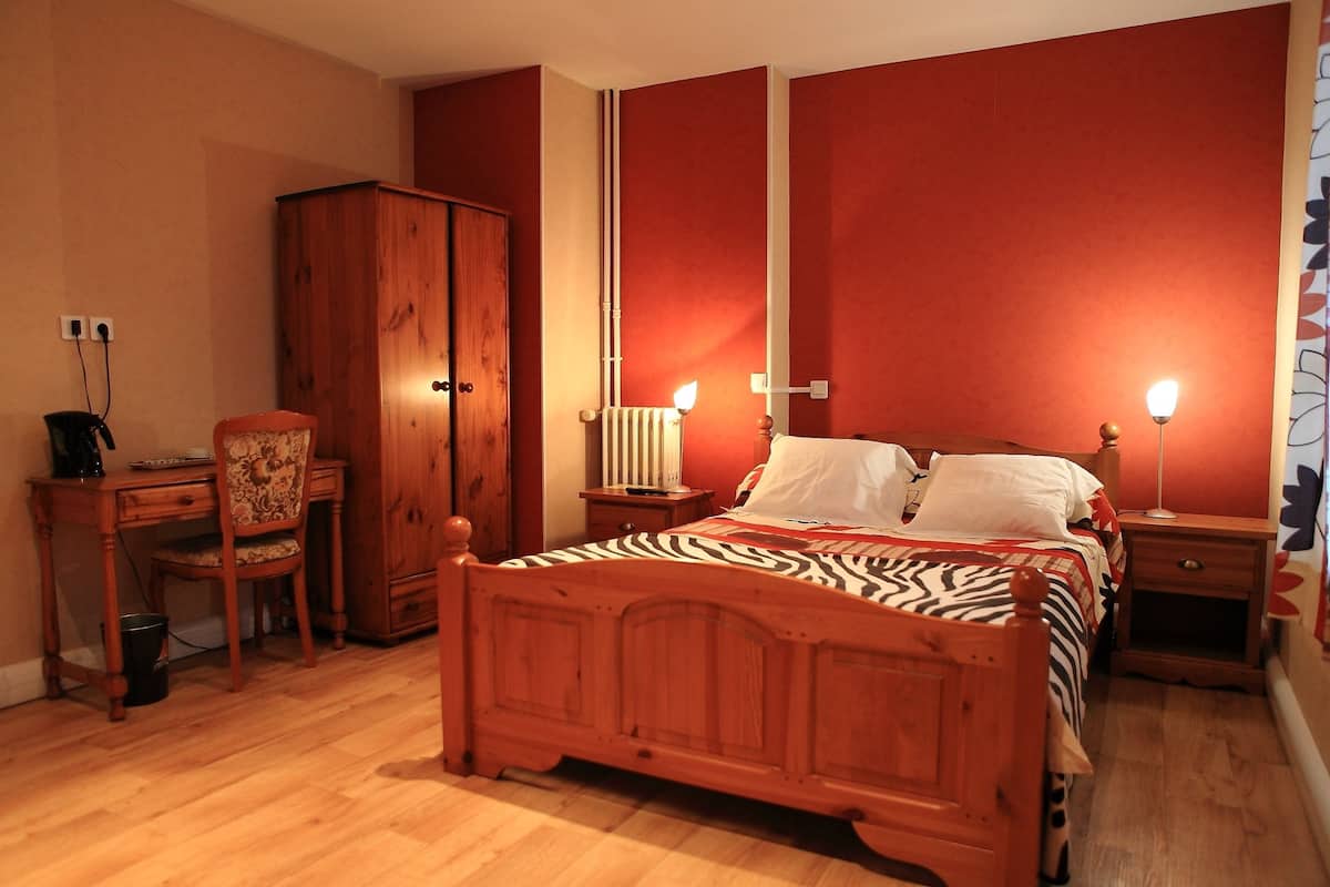 A bedroom with a wooden bed, a desk, and a chair.