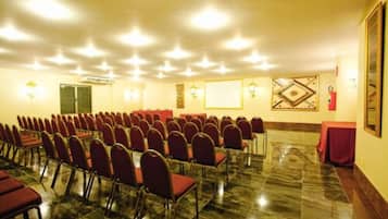 A conference room with rows of chairs, a marble floor, and wall-mounted lighting fixtures.