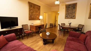 A living room with a television, red sofas, a wooden coffee table, and two paintings on the walls.