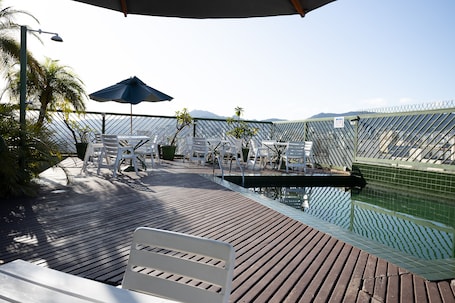 Una piscina al aire libre, sillones reclinables de piscina