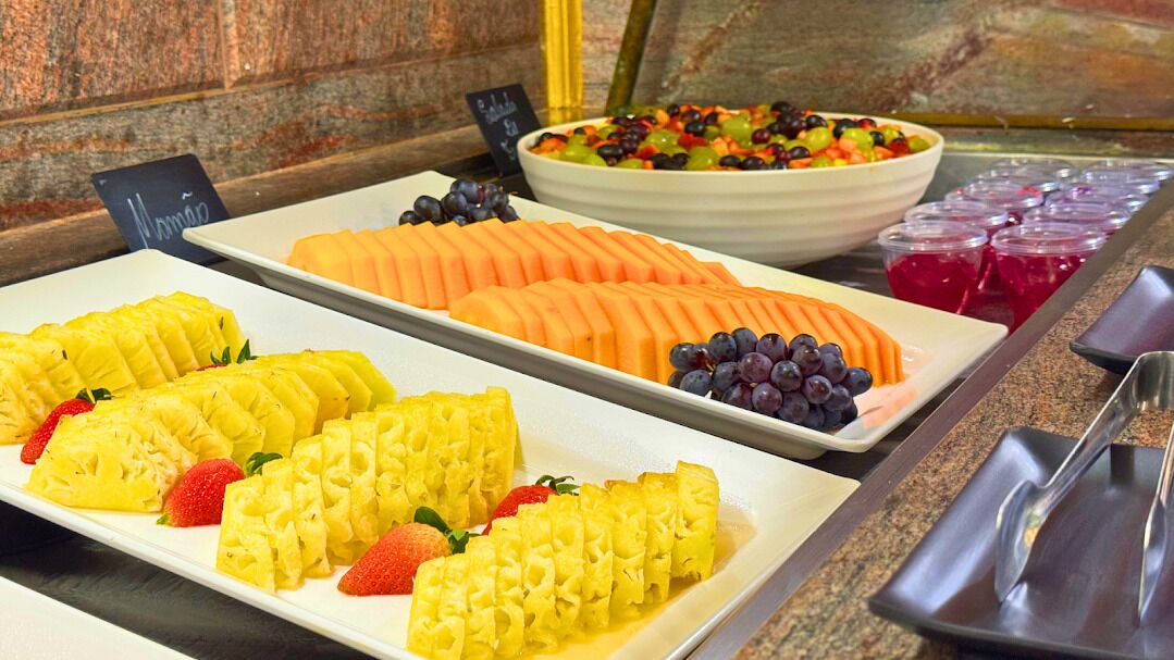 A buffet with various fruit platters including pineapple, cantaloupe, and grapes.