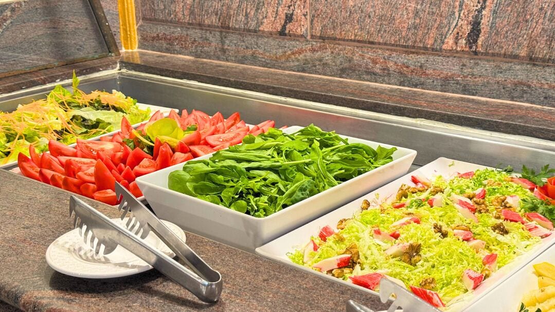 Un bufé con ensaladas y verduras variadas.