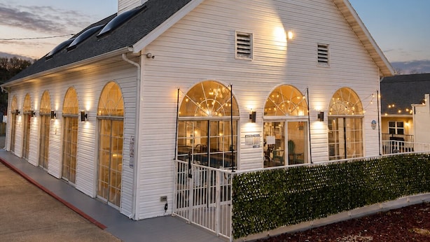 A white building with arched windows and a covered porch. - Carriage House Inn (Branson)