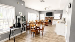 A modern kitchen with a dining area, wooden flooring, and ceiling fans. - Carriage House Inn (Branson)