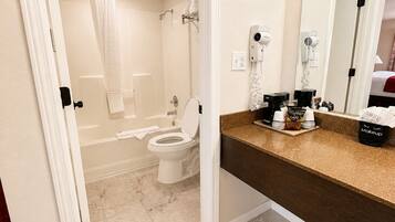 Un baño con inodoro, ducha y tocador con espejo.