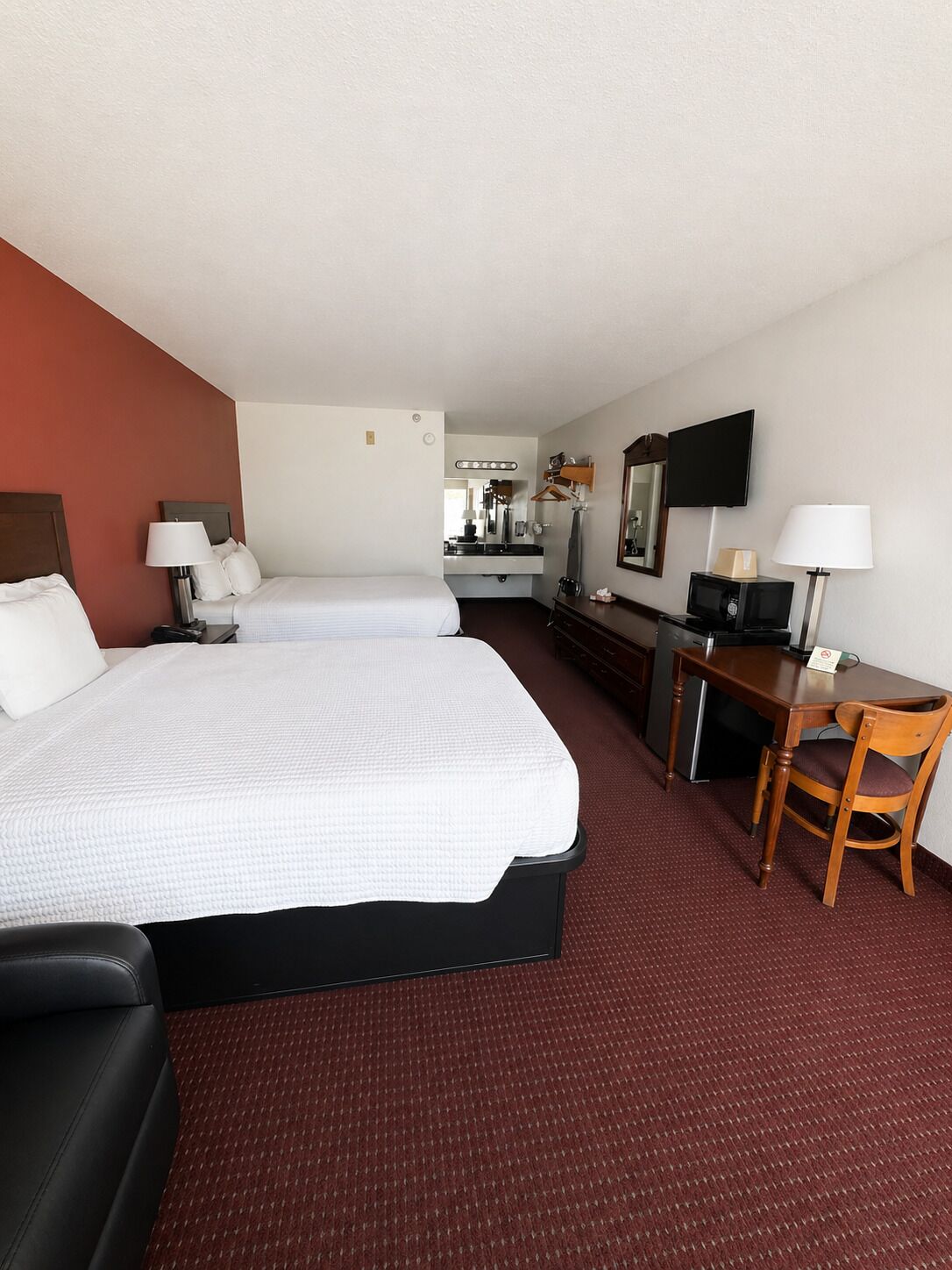 Une chambre d’hôtel avec deux lits, un bureau, une chaise, une télévision et une kitchenette.
