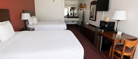Une chambre d’hôtel avec deux lits, un bureau, une chaise, une télévision et une kitchenette.