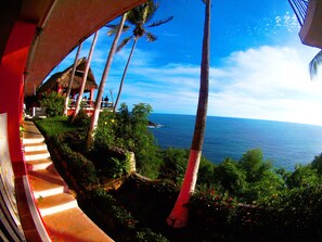 A view of a coastal area with palm trees, a thatched-roof structure, and a staircase leading down to the beach. - Hotel Los Flamingos (Acapulco)