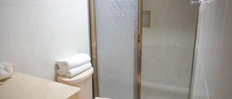 Un baño con inodoro, lavamanos y zona de ducha.