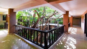 A covered corridor with a central garden area featuring a large tree and a black railing. - Hotel Colonial Cancun (Cancun)
