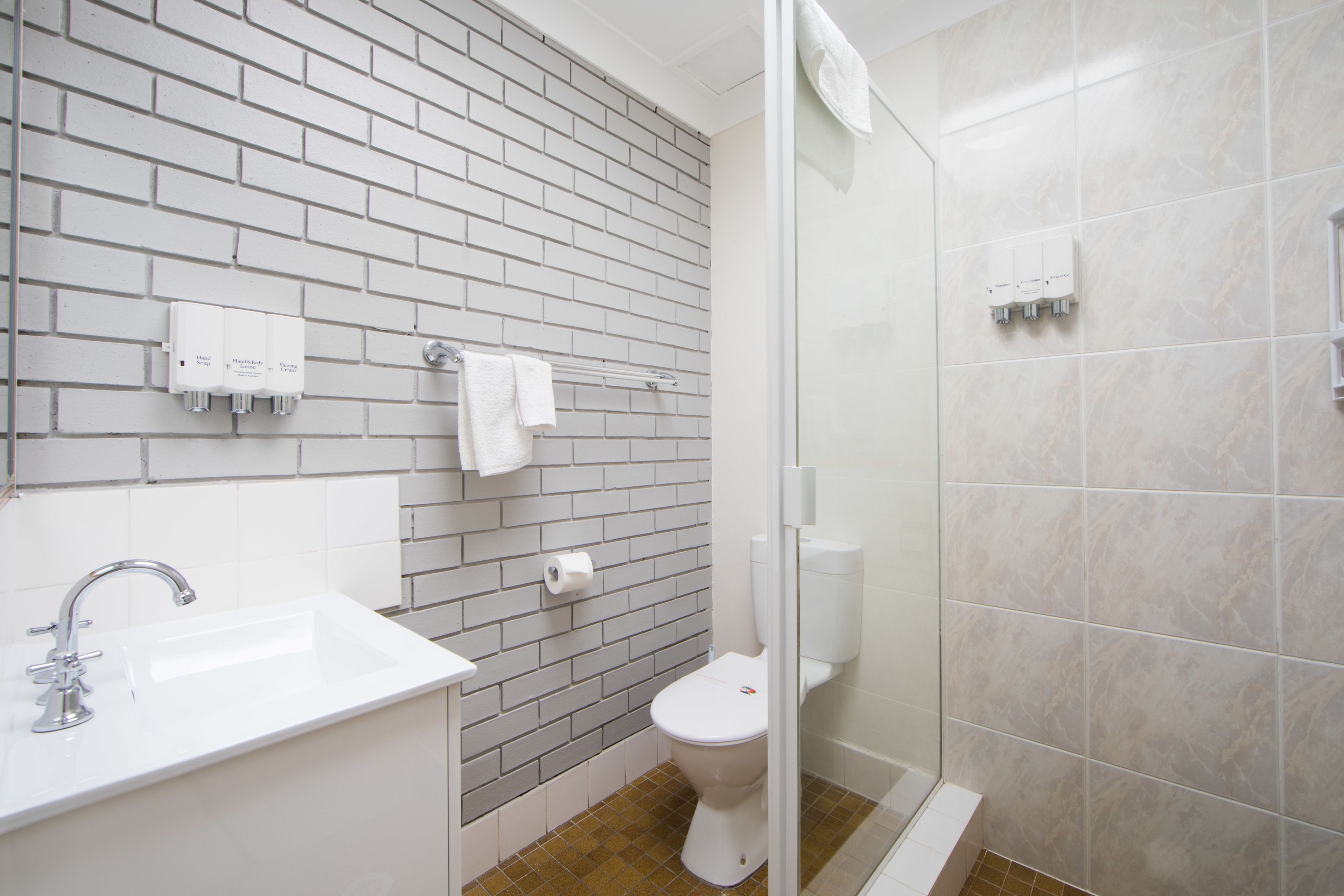 Een badkamer met een witte wastafel, toilet en een douchecabine van glas.