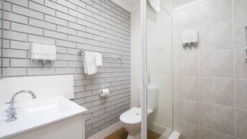 Een badkamer met een witte wastafel, toilet en een douchecabine van glas.