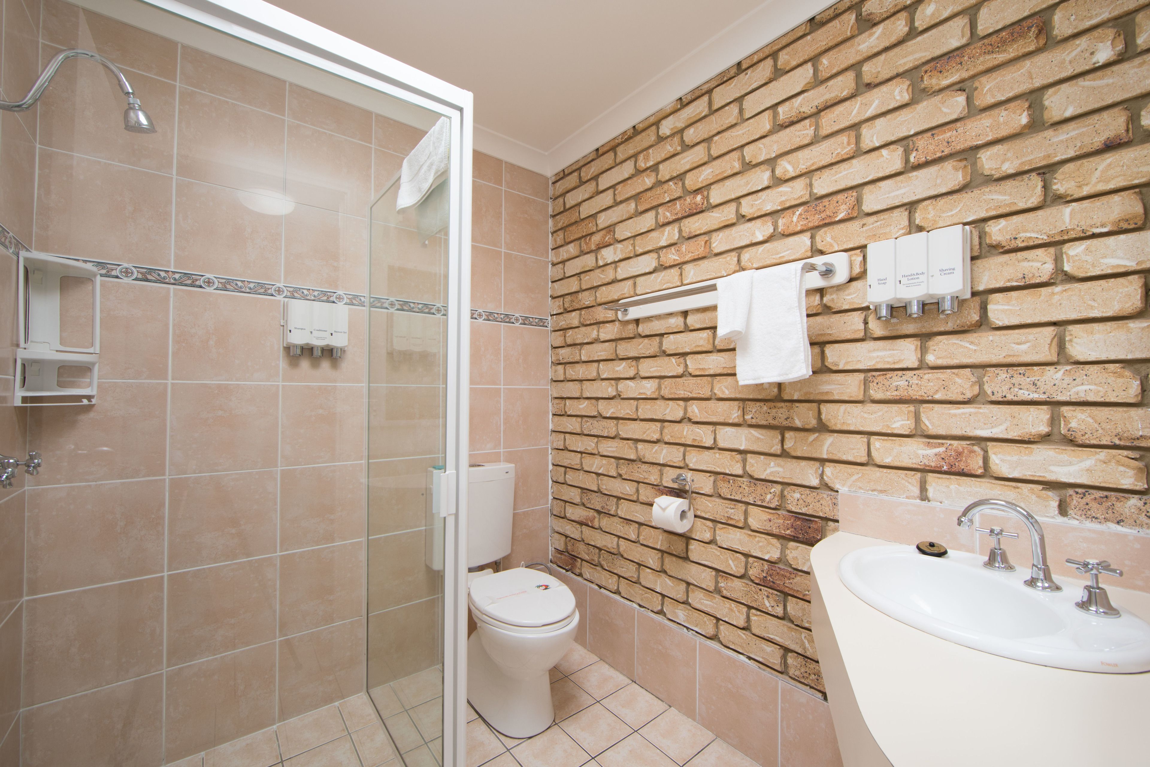 Een badkamer met een glazen douchecabine, toilet en wastafel met spiegel.
