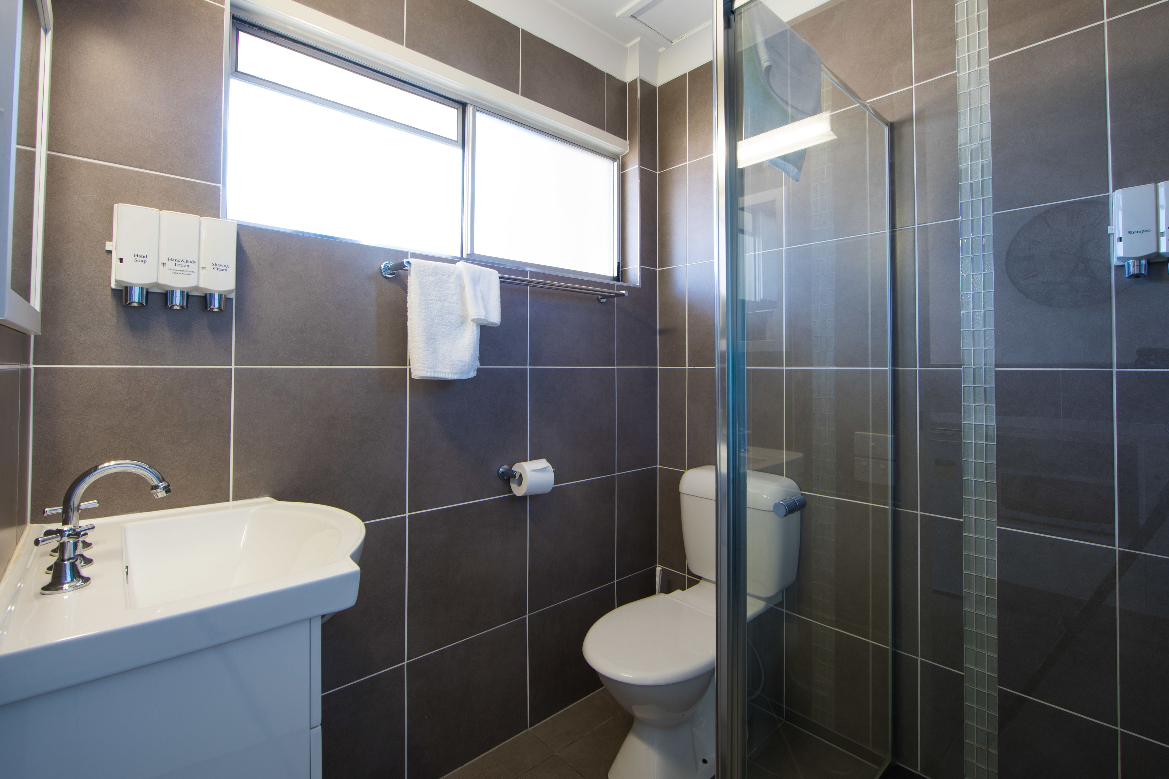 A modern bathroom with a white sink, a toilet, and a glass shower enclosure.