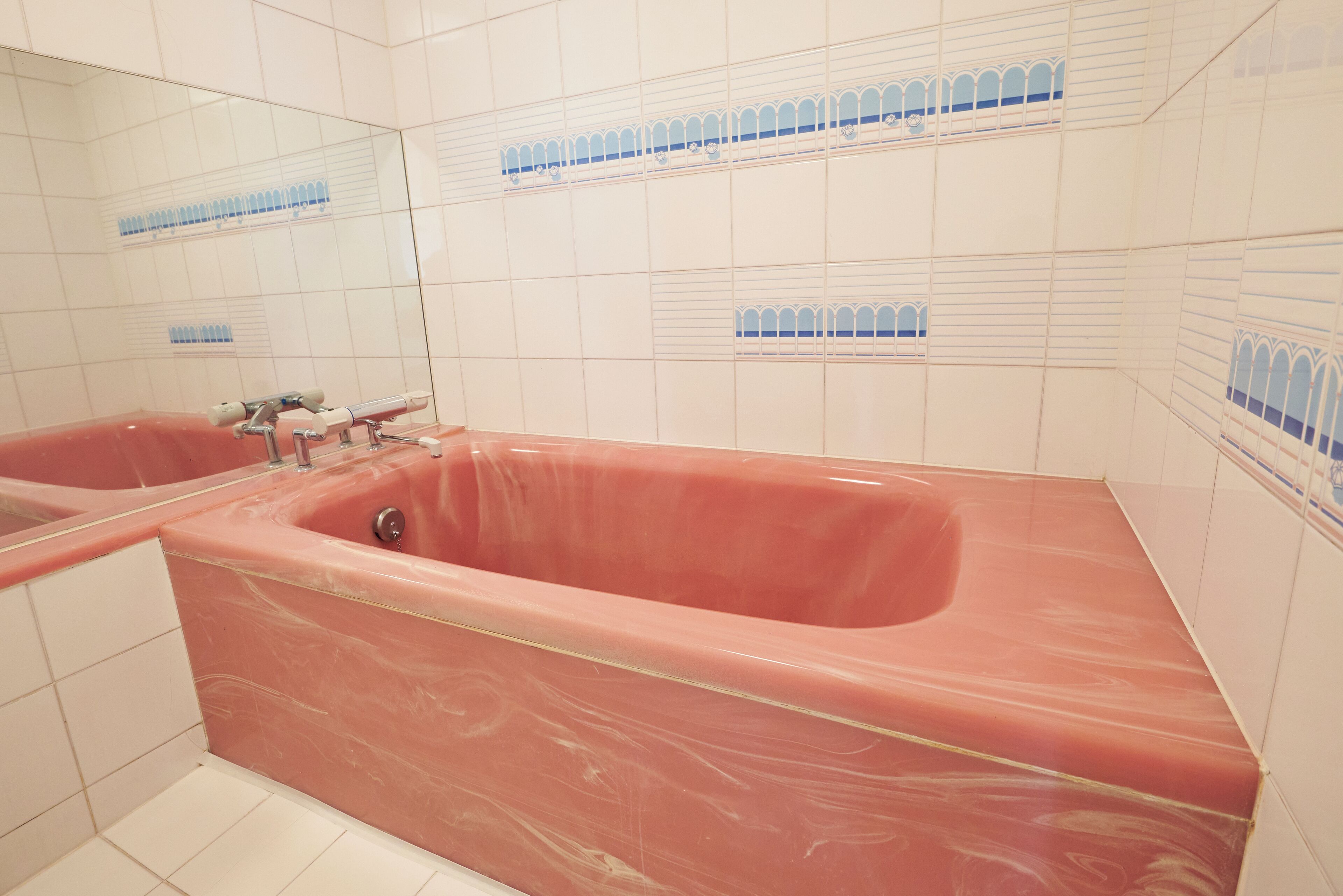 Ein Badezimmer mit einer großen Marmortonne, weißen Fliesenwänden und einer Spiegelwand.