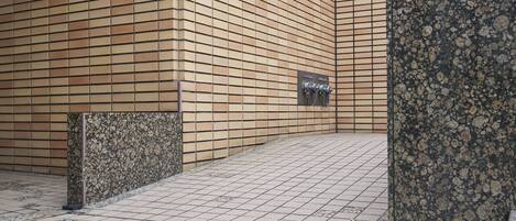 A tiled walkway with a brick wall and a metal sign.
