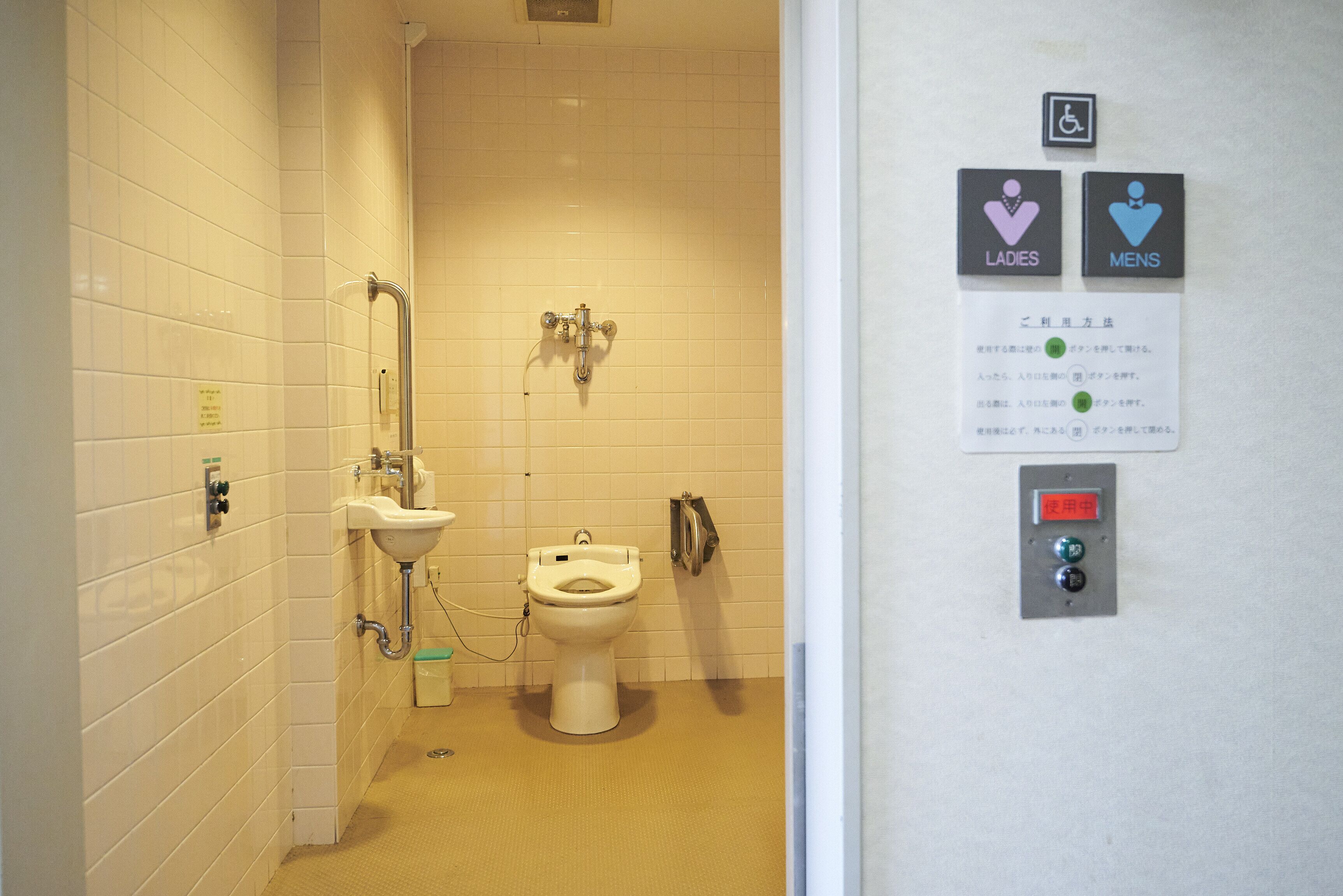 A restroom with a toilet, sink, and hand dryer. There are signs indicating ladies and mens facilities.
