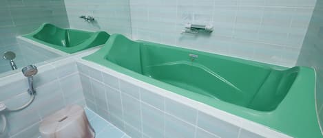 A bathroom with two green sinks, a bathtub, and a shower.