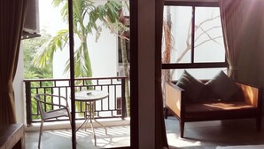 A room with a balcony, a round table, and a sofa with cushions. - Mandala House (Chiang Mai)