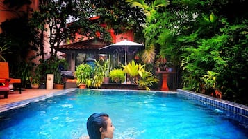 Una piscina al aire libre, sillones reclinables de piscina