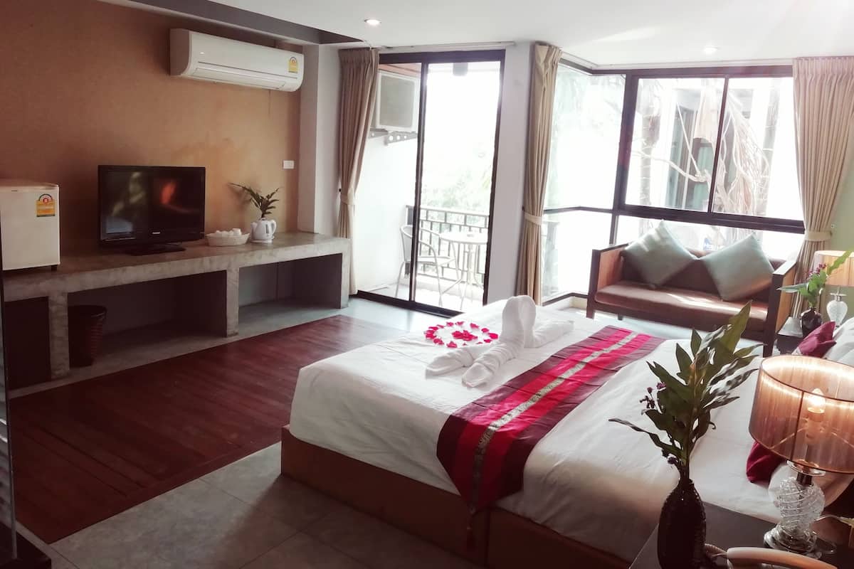 A hotel room with a bed, a TV, a desk, a chair, a balcony, and a window.