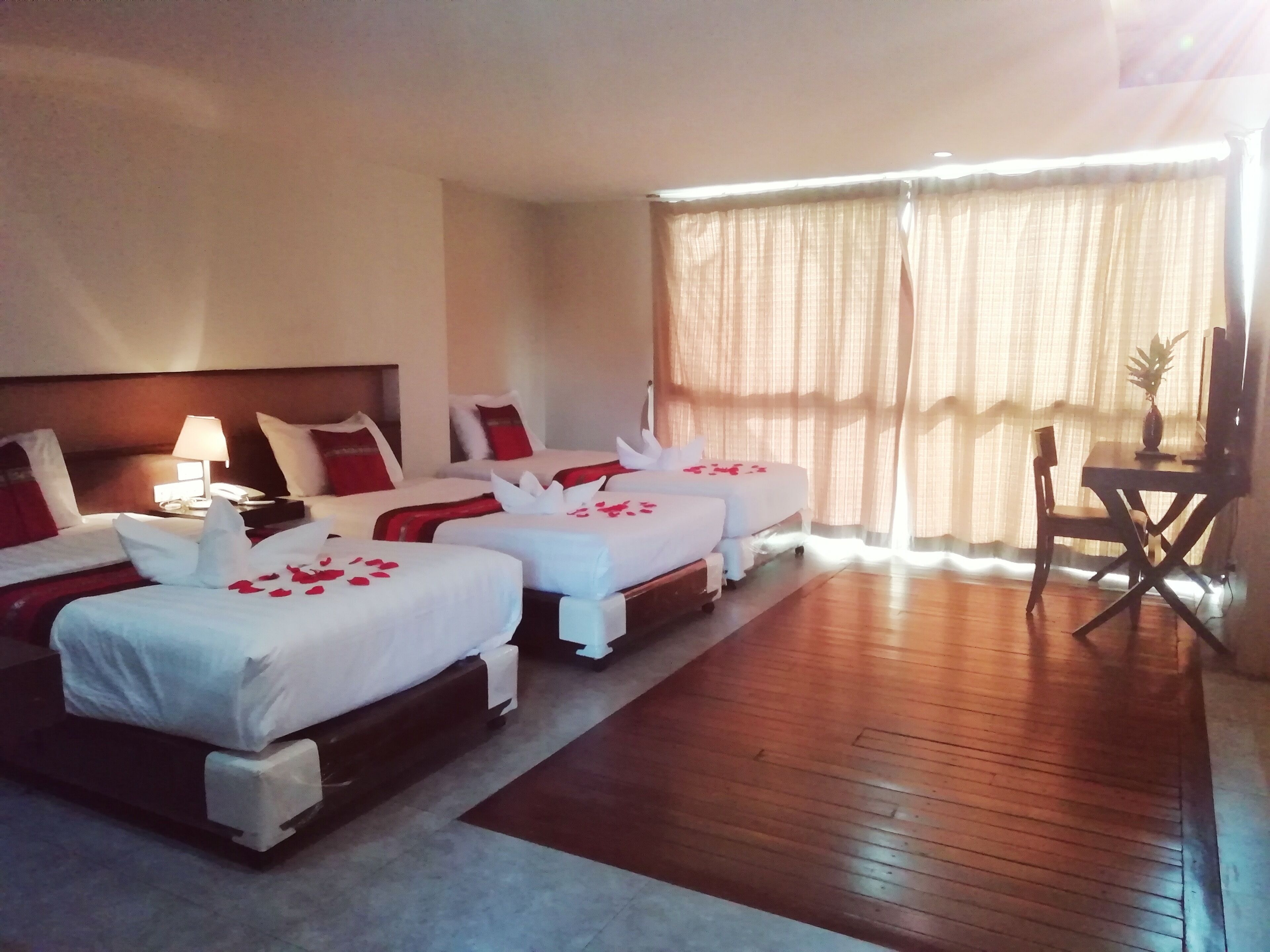 A hotel room with four beds, a desk, and a chair.