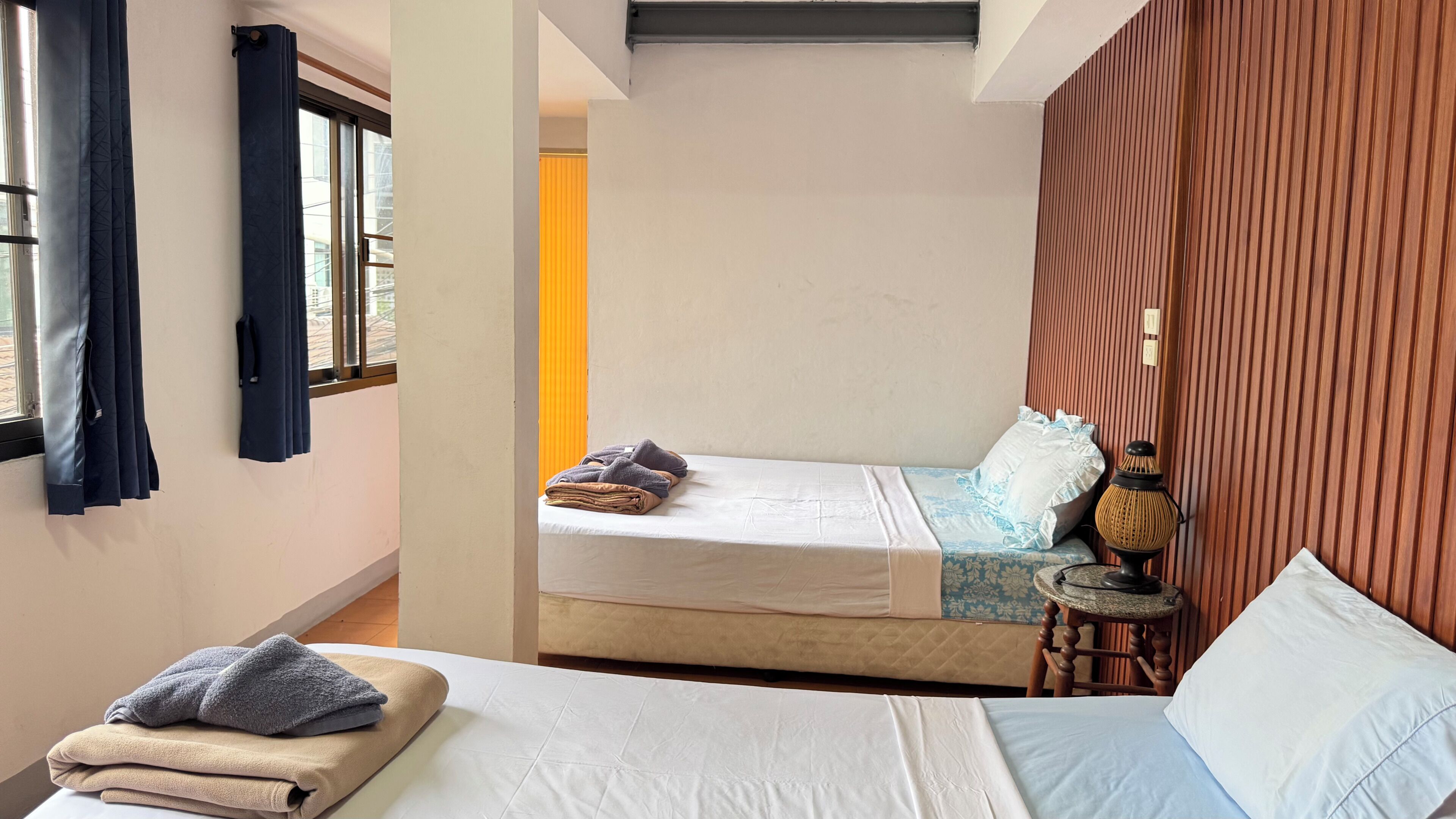 Una habitación con una cama, una mesita de noche con lámpara y una ventana con cortinas.
