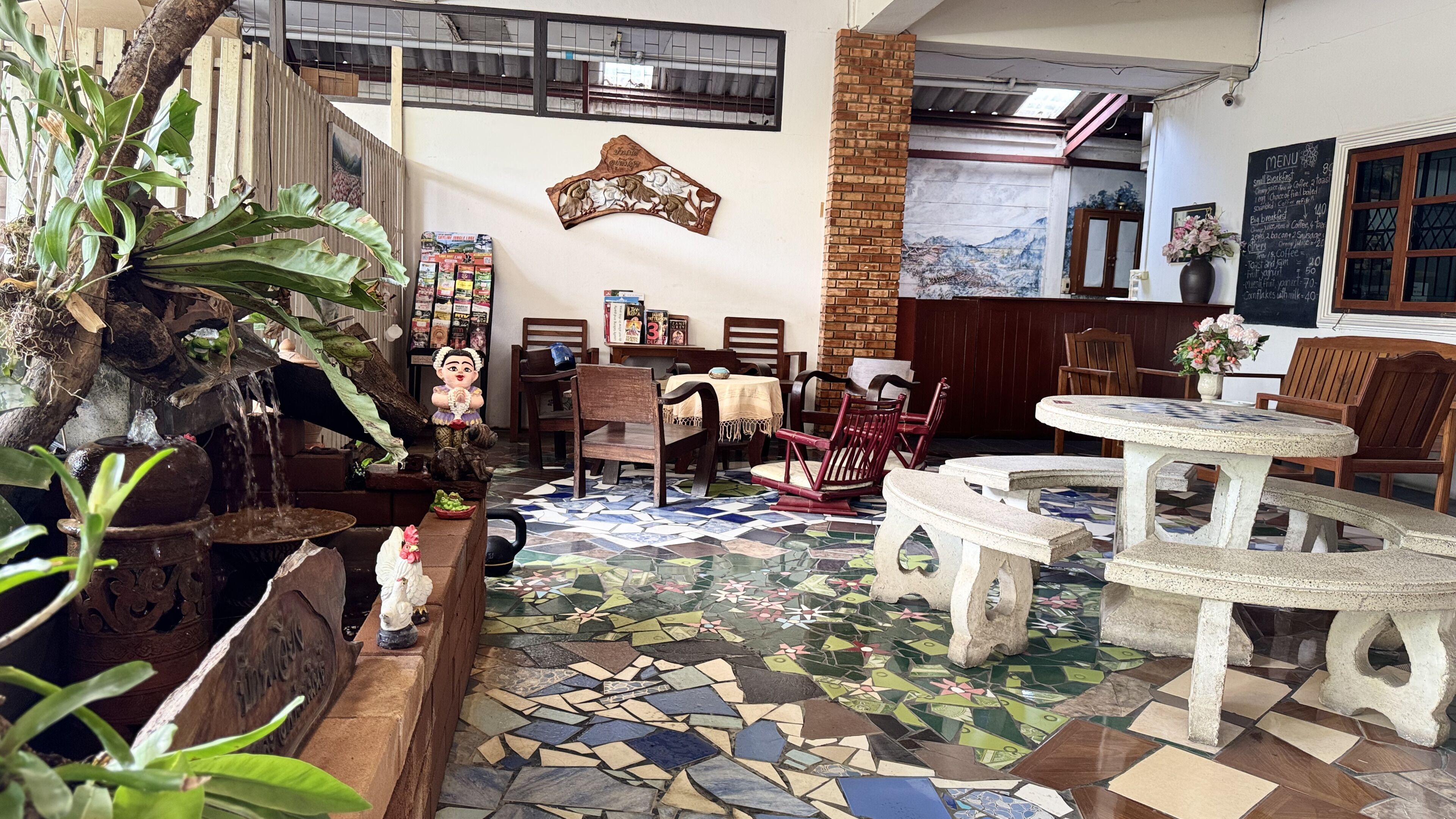 A cozy cafe with a mosaic floor, wooden furniture, and a decorative wall.