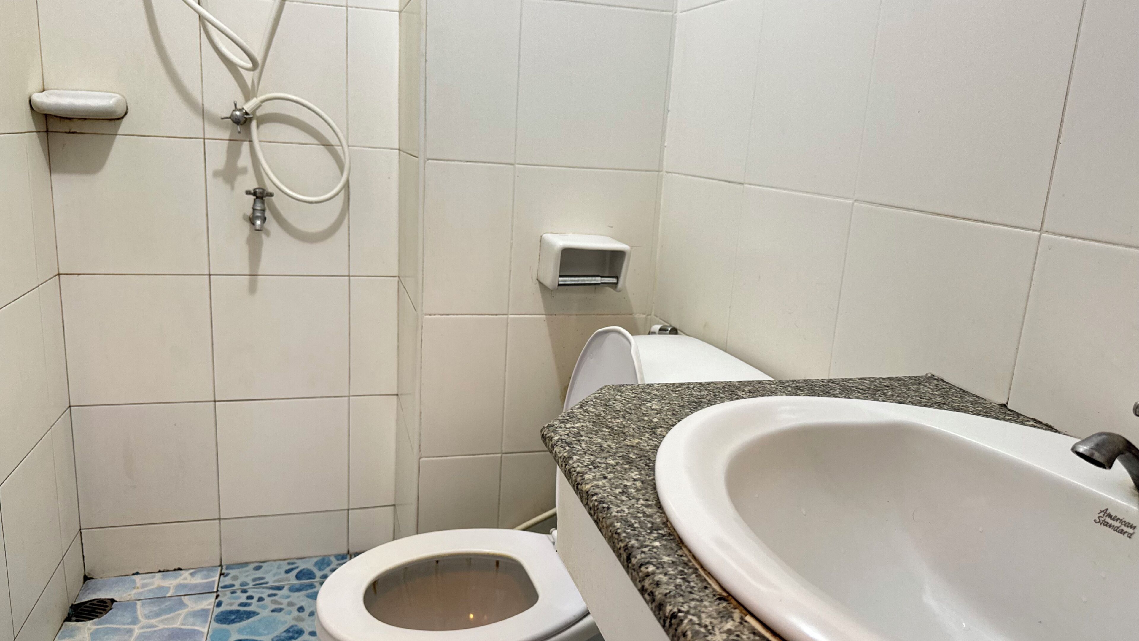 Un baño con inodoro, lavamanos y secador de manos.