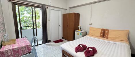 Un dormitorio con cama, escritorio, silla, armario y balcón.