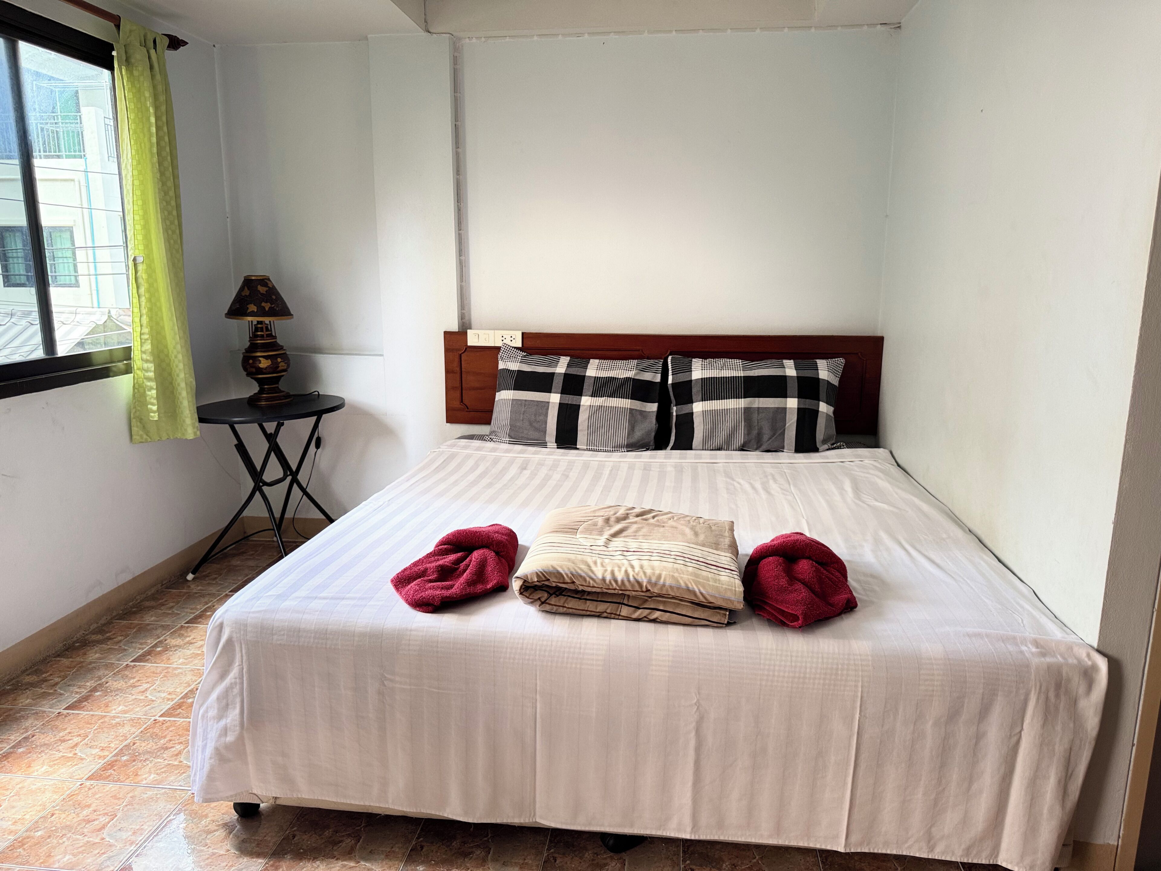 A neatly made bed with a striped bedspread, two pillows, and two folded towels.
