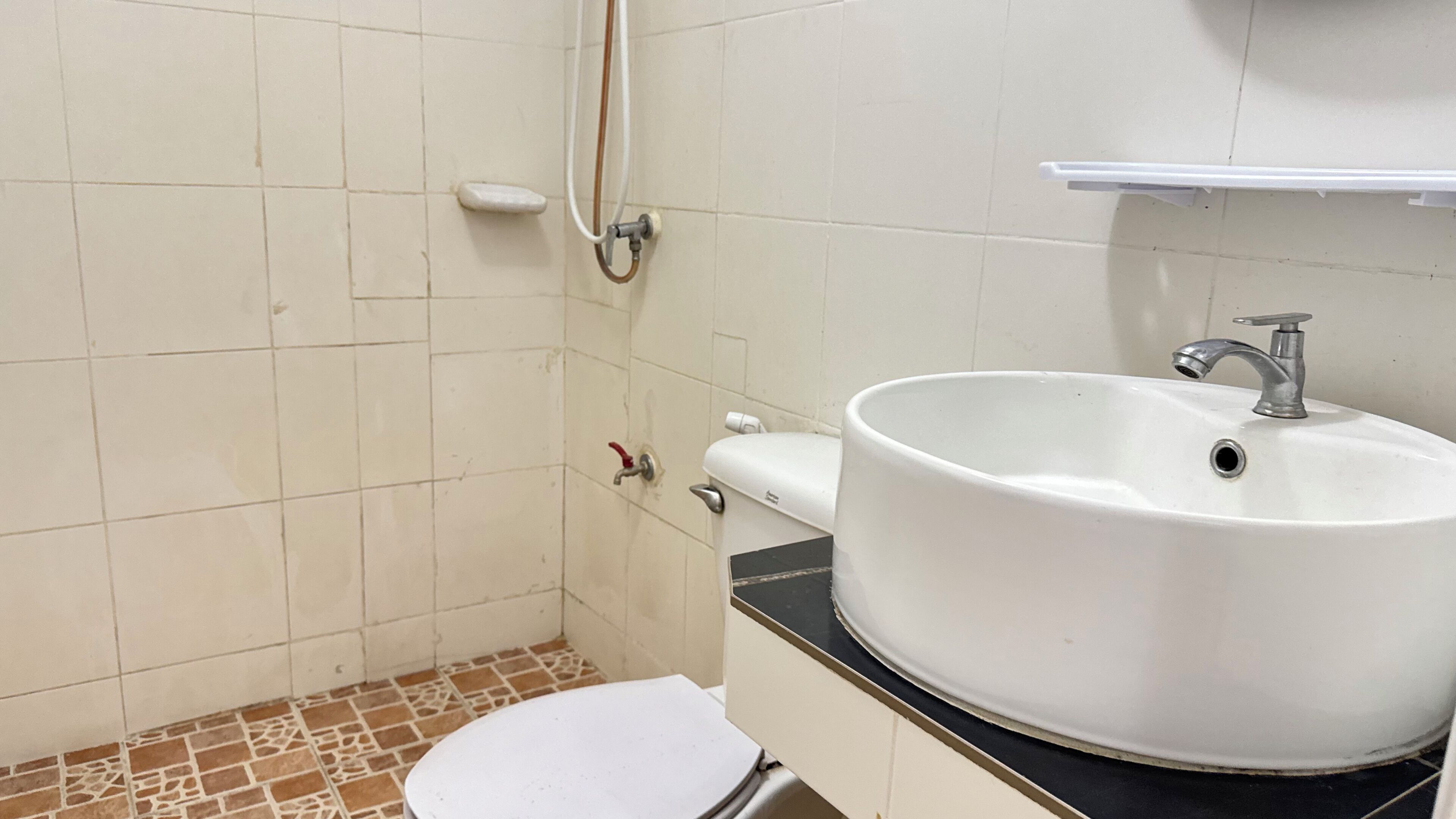 Un baño con lavamanos blanco, inodoro y zona de ducha.