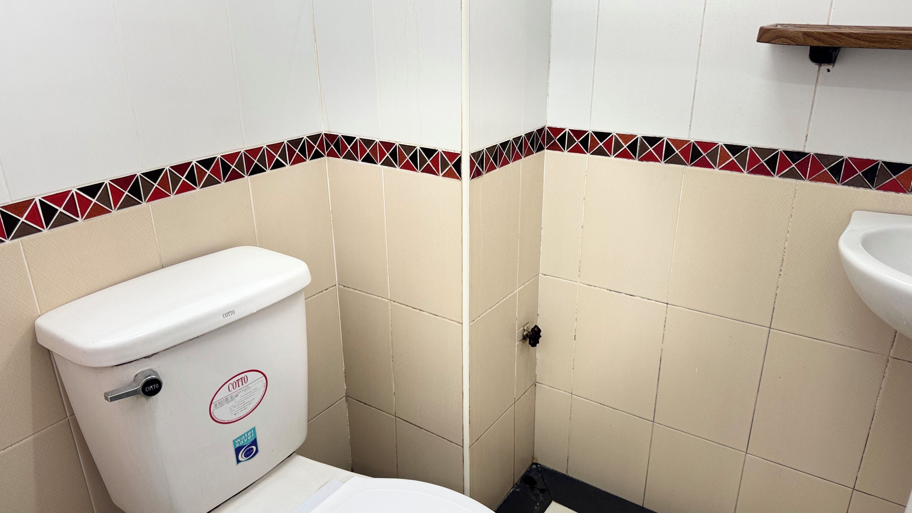 A bathroom with a toilet, a sink, and a tiled wall with a decorative border.