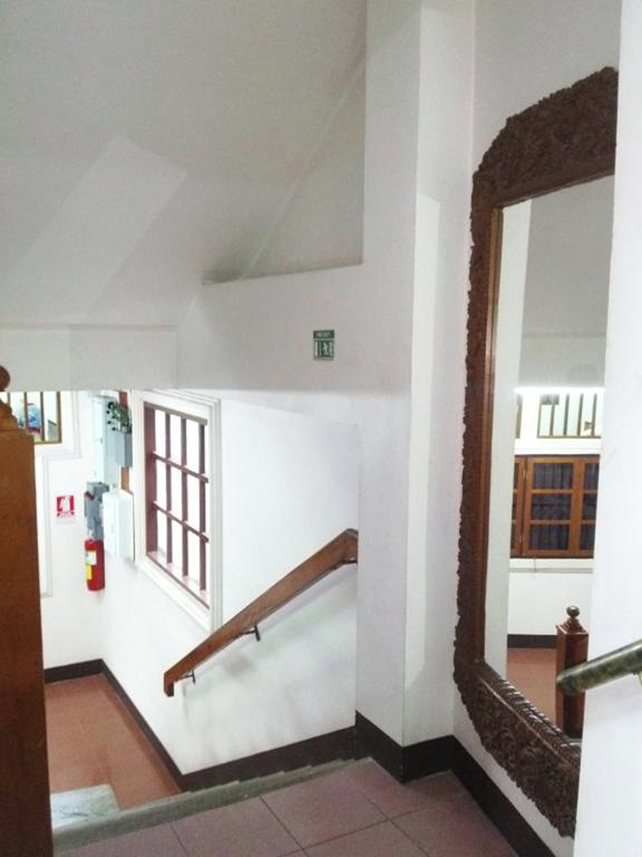 A staircase with a wooden handrail and a large ornate mirror on the wall.