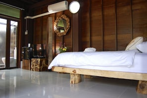 Une chambre à coucher avec un lit en bois, une télévision et un miroir au mur.
