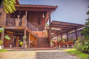 Une maison en bois avec un balcon, un escalier et un espace salon extérieur.