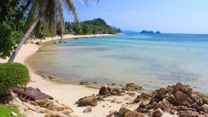 A beach with clear turquoise water, rocky shoreline, and palm trees. - Beyond The Blue Horizon Villa Resort (Ko Pha-ngan)
