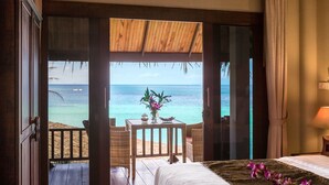 A bedroom with a view of the ocean, a wooden ceiling, a bed with a floral arrangement, and a small table with chairs. - Beyond The Blue Horizon Villa Resort (Ko Pha-ngan)