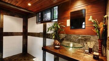Une salle de bain avec un plafond en bois, un lavabo en forme de bol en verre, une plante en pot et un miroir.