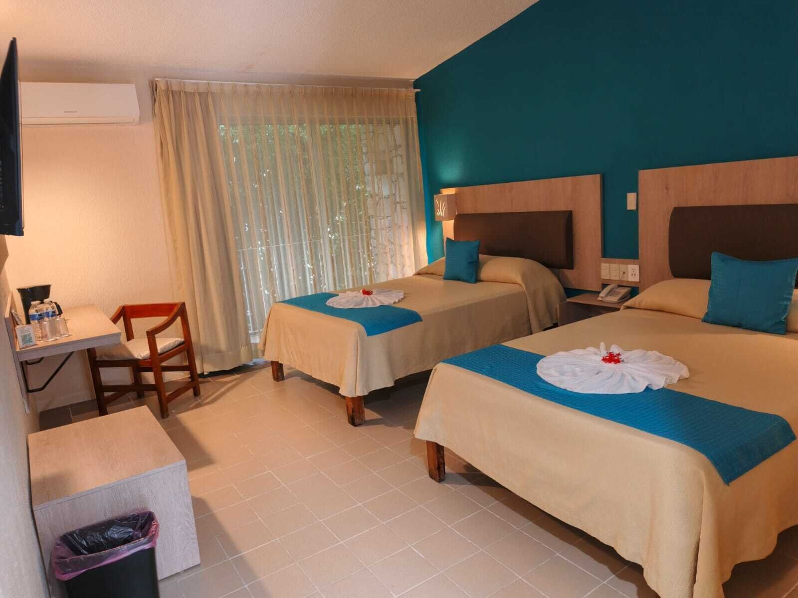 Habitación de hotel con dos camas, un escritorio, una silla y un cesto de basura.