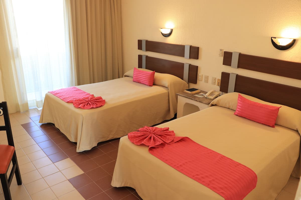 Two double beds with matching headboards and bedside tables, each with a lamp and a telephone.