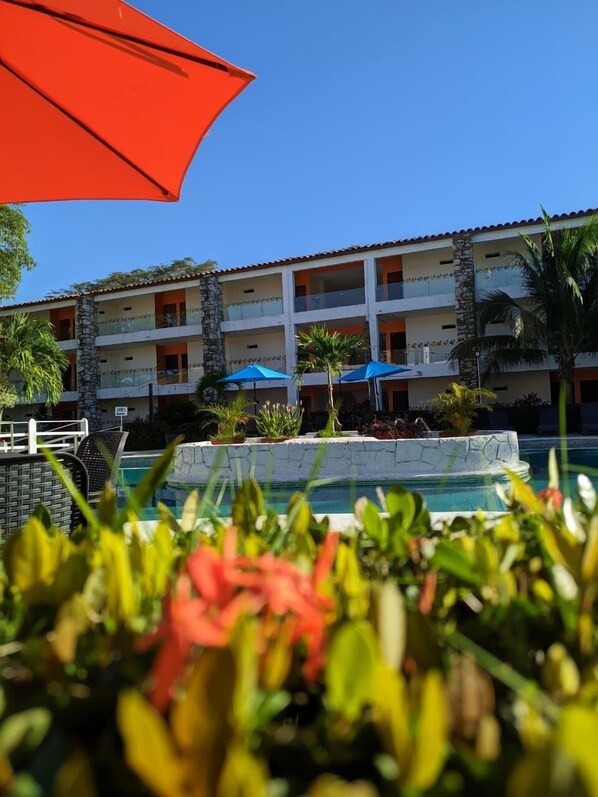 A hotel with a pool, surrounded by tropical plants and umbrellas. - Hotel Plaza Palenque (Palenque)
