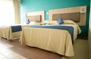Habitación de hotel con dos camas, cada una con cabecero y almohadas.