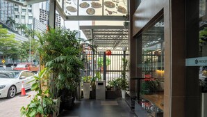 A hotel entrance with a covered walkway, potted plants, and a glass door. - Prescott Hotel Bukit Bintang (Kuala Lumpur)