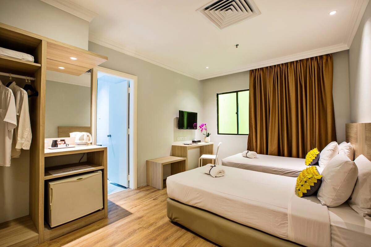 A hotel room with a bed, a desk, a wardrobe, and a television.