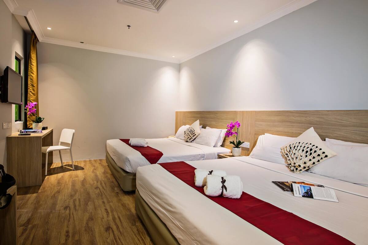 A hotel room with two beds, a desk, and a chair.