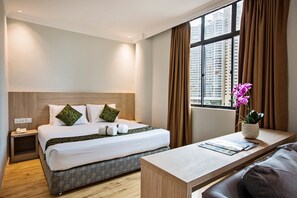 A hotel room with a neatly made bed, a bedside table with a vase of flowers, and a view of the city through large windows. - Hotel Zambuger Wira Kuala Lumpur (Kuala Lumpur)
