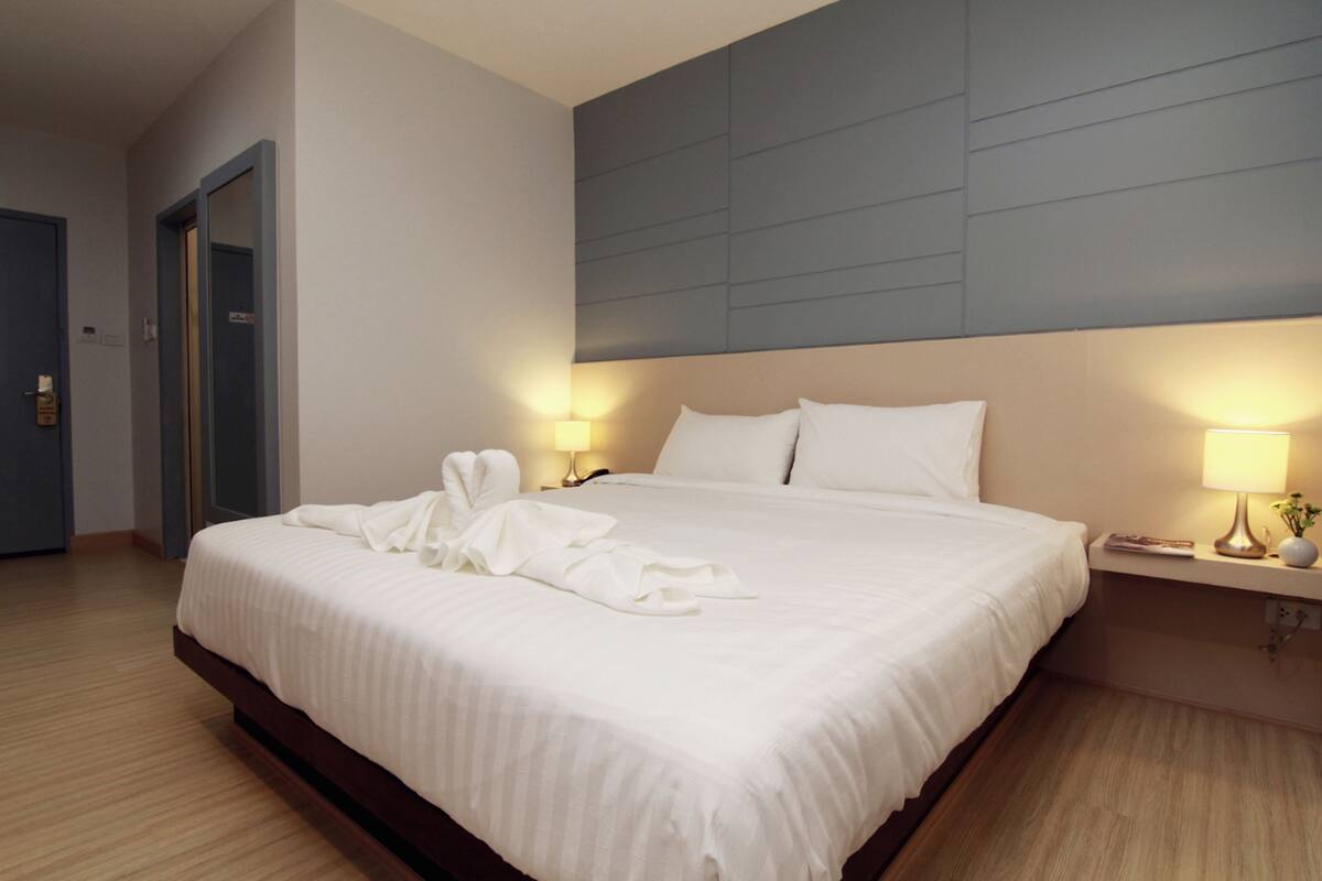 A hotel room with a large bed, two bedside lamps, and a headboard.