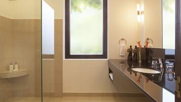 Un bagno moderno con cabina doccia in vetro, un'ampia finestra e un lavabo con specchio su un piano d'appoggio nero.