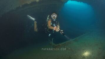 Un buceador bajo el agua en una cueva, con una linterna y una cámara.